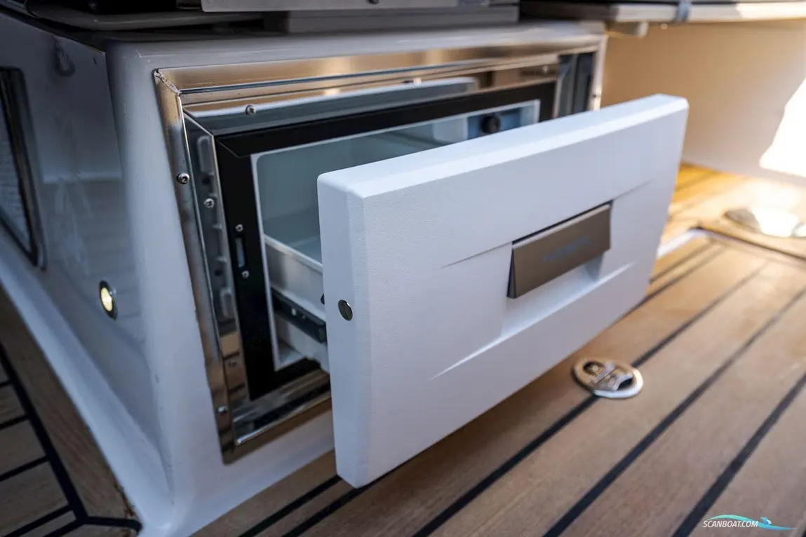 A modern boat kitchen with an opened white drawer freezer, showcasing sleek design and stainless steel accents.
